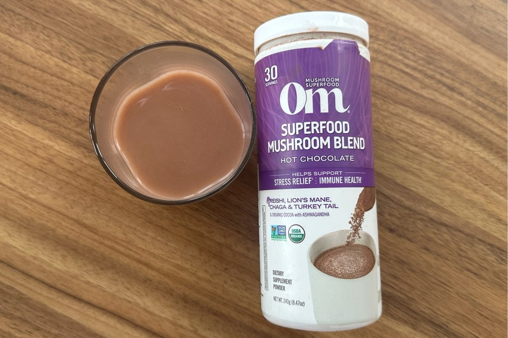 A bottle of mushroom blend next to a glass of chocolate liquid