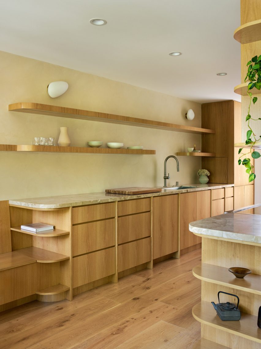 A kitchen featuring oak cabinetry, open shelving and beige Barbados marble