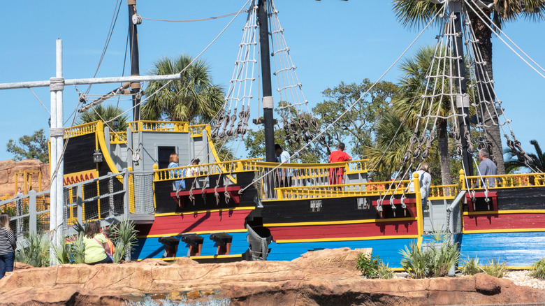 Mini-golfers climb on a red, blue, and yellow pirate ship at a miniature golf course in Myrtle Beach.