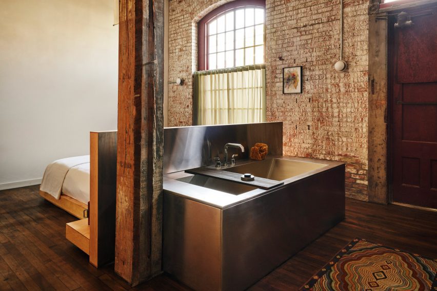 Guest bedroom with exposed brick walls and a stainless steel bathtub