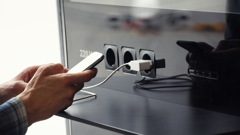 Man holding a phone connected to a public charging station