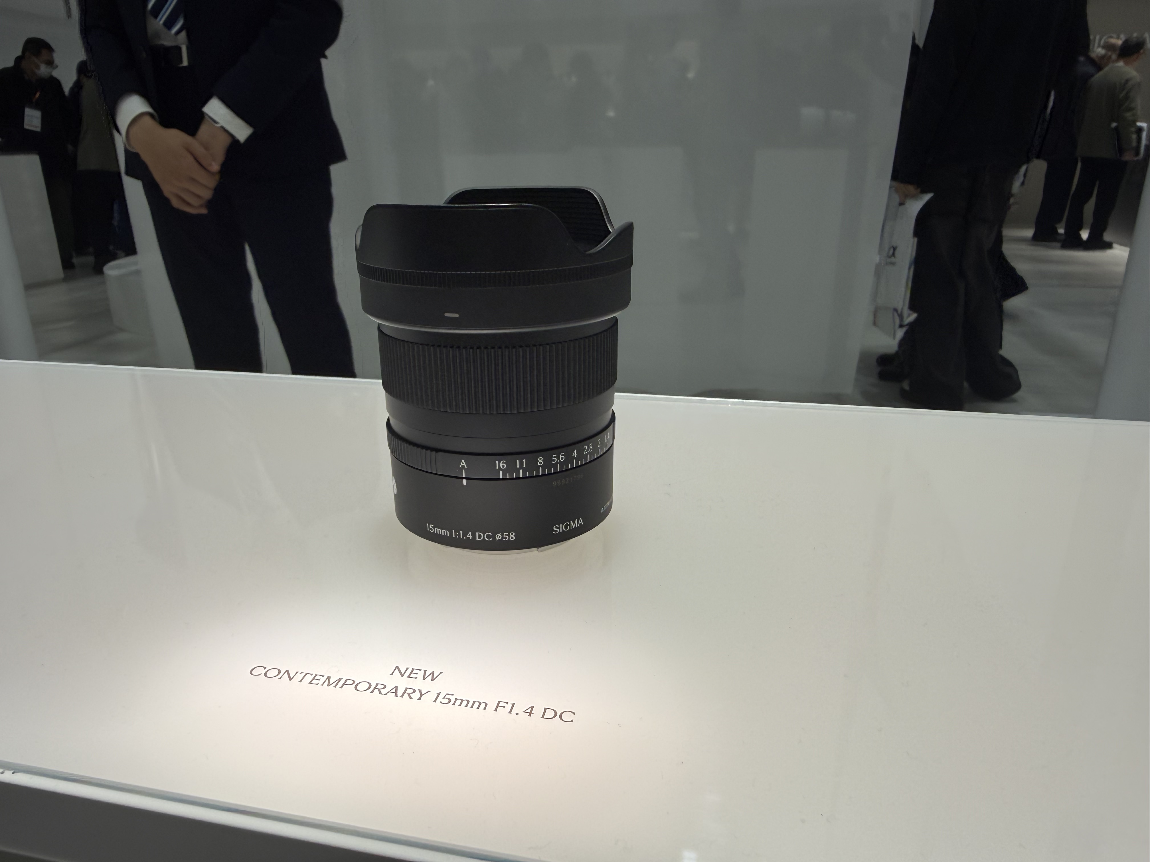 Sigma's 15mm F1.4 DC Contemporary lens on a white display surface at the CP+ 2026 show in Japan
