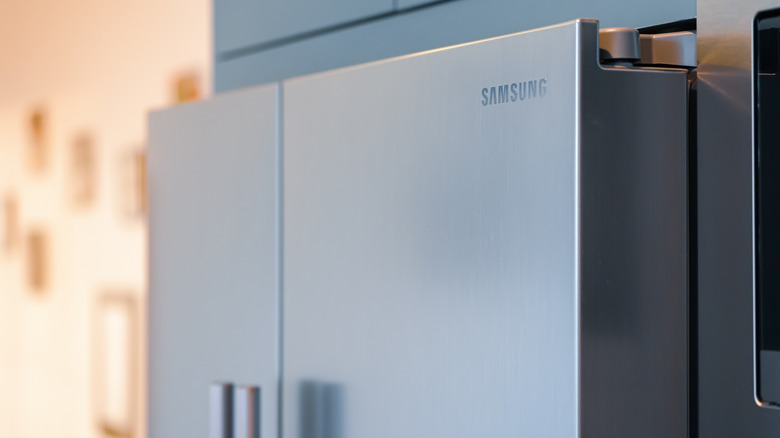 A side profile of a stainless steel fridge with the Samsung logo visible in the top right of the right side door