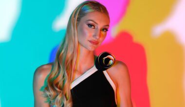 Cameron Brink with long blonde hair in a black and white dress stands against a colorful, abstract background.
