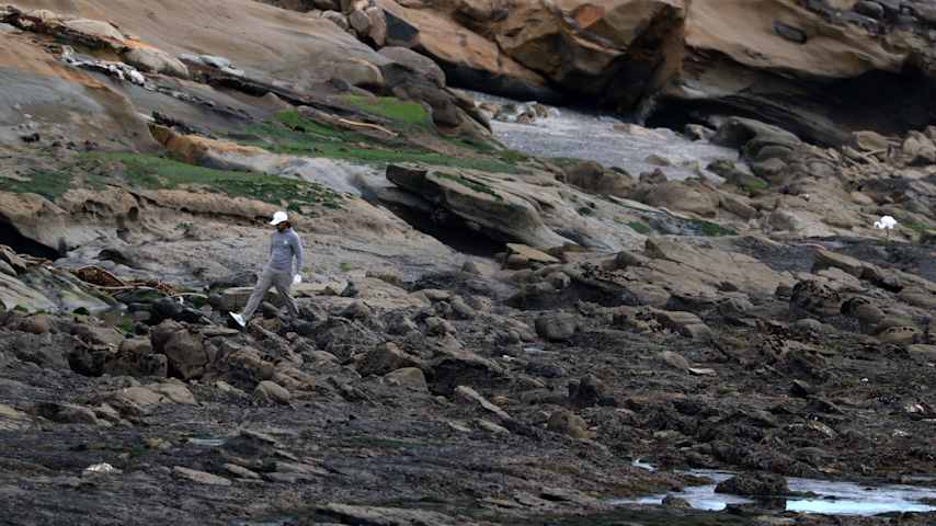 Tommy Fleetwood looks for his ball on the beach on the 18th hole during Round 2 of the AT&T Pebble Beach Pro-Am. (Jed Jacobsohn/Getty Images)