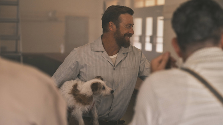 Simon Baker as Keith Mulvaney holding a dog in The Narrow Road to the Deep North
