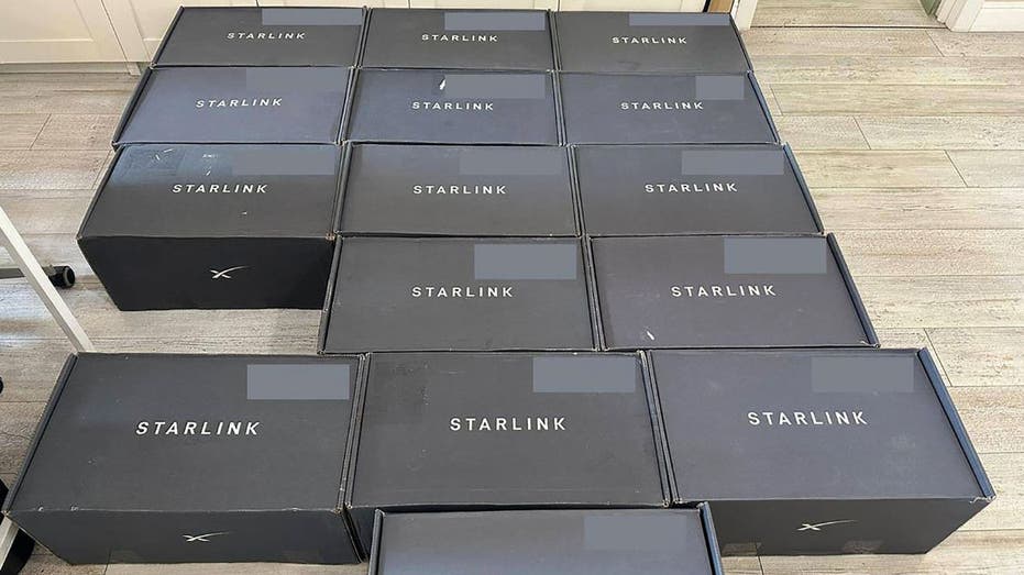 Multiple black Starlink boxes laid out in rows on a floor, each box marked 
