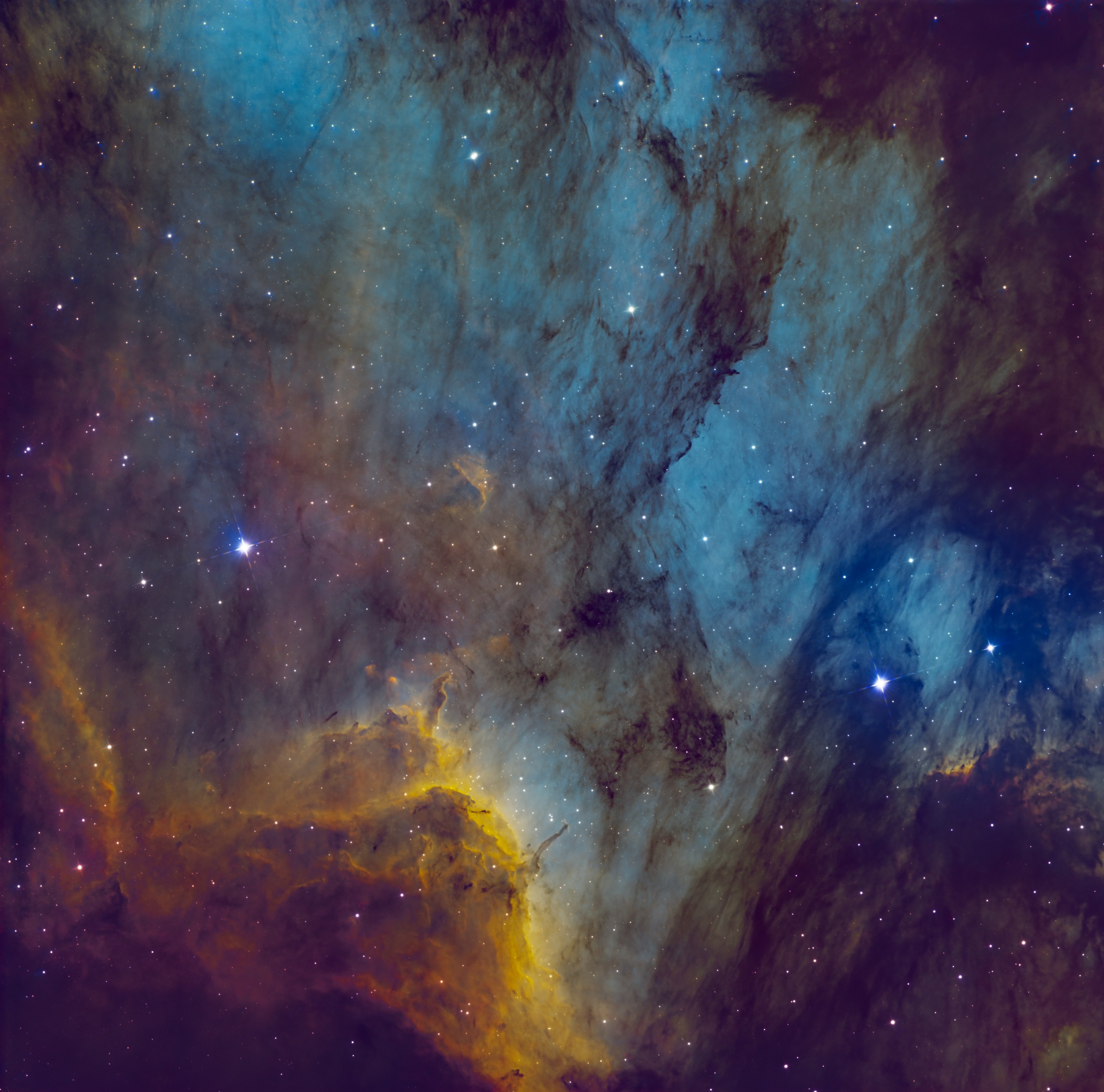 White-blue stars are pictured shining against a nebula backdrop, which is a mixture of colorful gas overlaid by a dark dusty cloud.