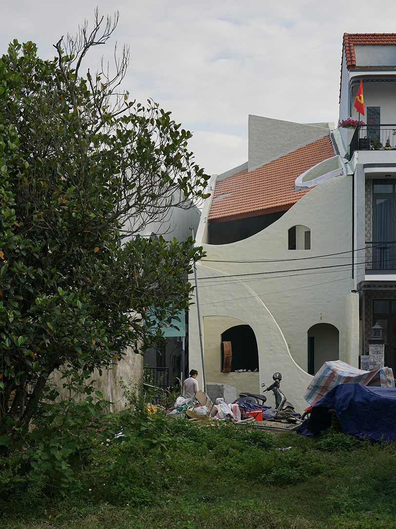 curved cutouts sculpt fluid voids within gabled residence in vietnam