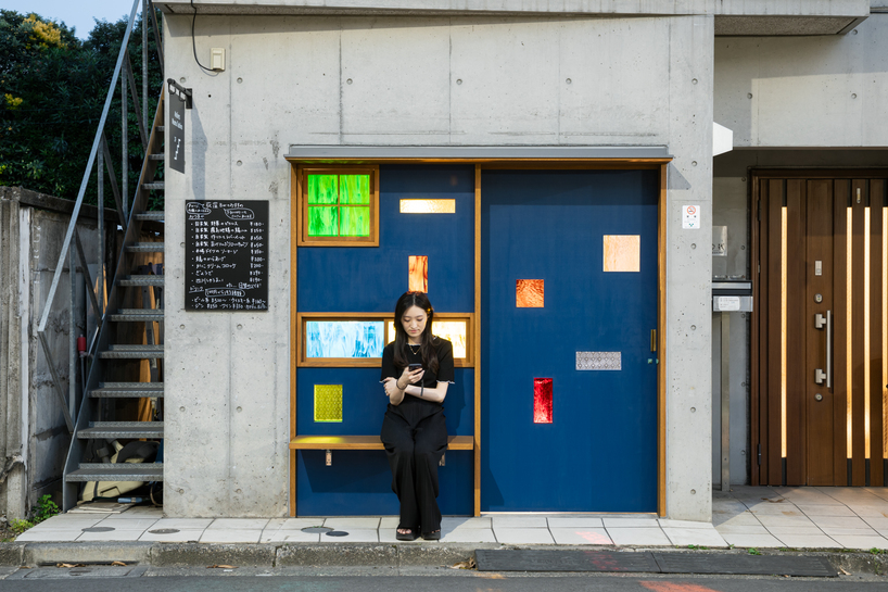 colored glass apertures reveal lively tokyo bar through bright blue entrance