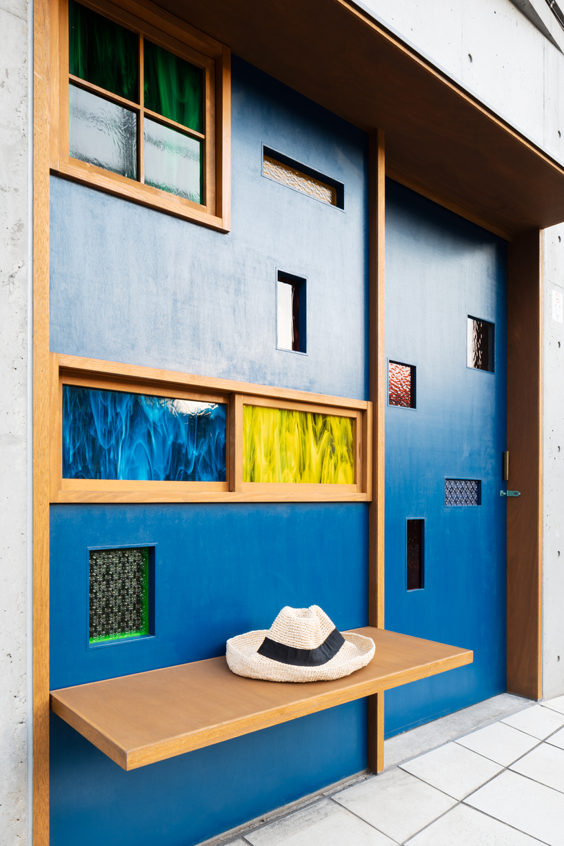 colored glass apertures reveal lively tokyo bar through bright blue entrance