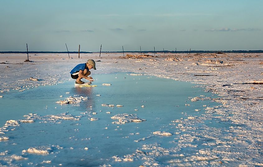 Young boy collecting salt crystals from salt-saturated water at Salt Plains National Wildlife Refuge in Oklahoma