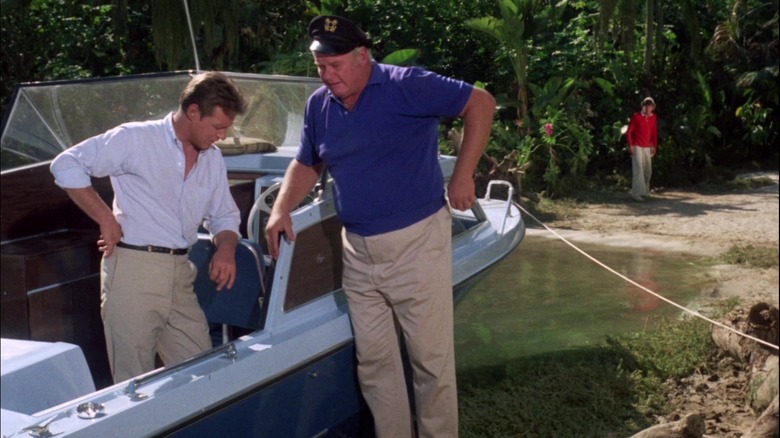 The Skipper and the Professor next to a small boat with Gilligan in the background on Gilligan's Island
