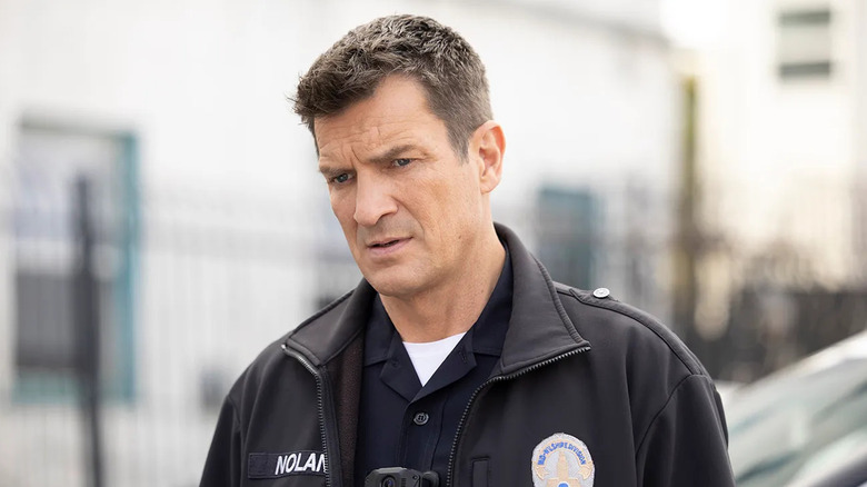 John Nolan (Nathan Fillion) looks downcast while standing outside in his police uniform in The Rookie