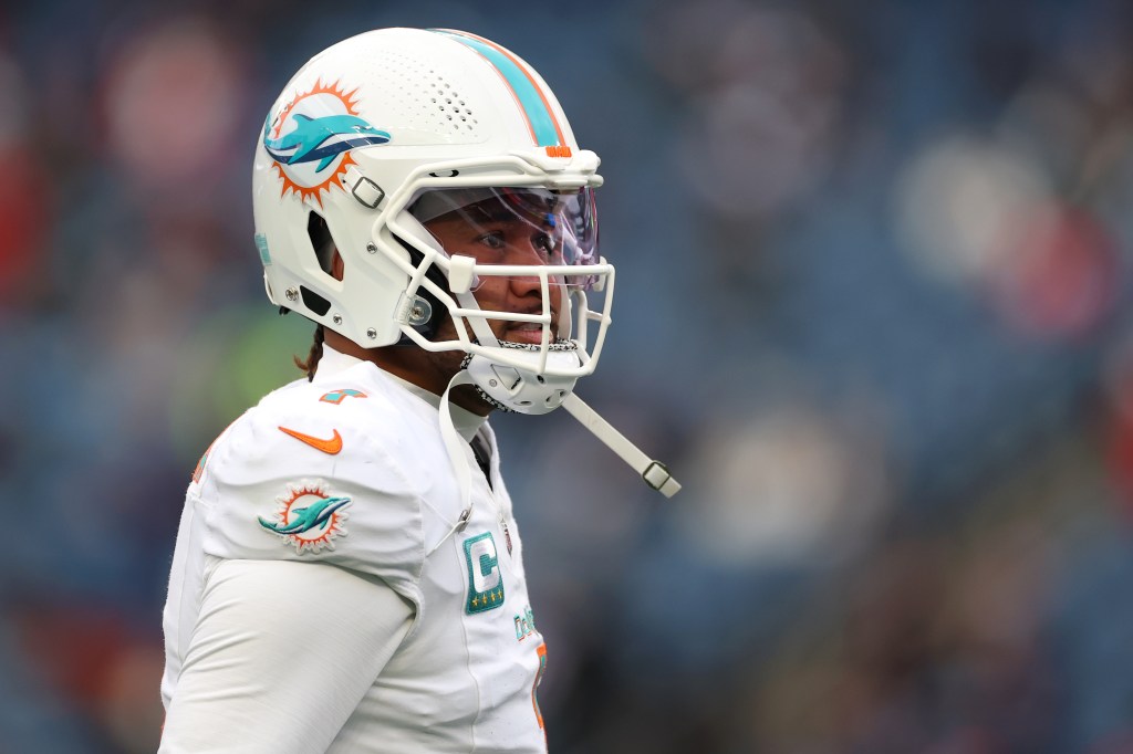 Miami Dolphins quarterback Tua Tagovailoa in his white uniform and helmet warming up on the field.