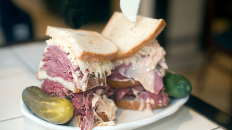 overstuffed sandwich on rye with pickles on the side