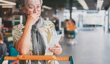 A person grocery shopping, looking down at their list and appearing concerned.