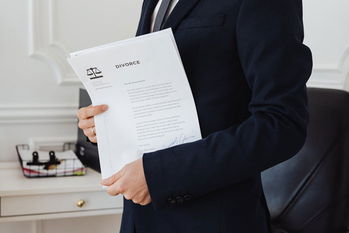 Person in a suit holding a divorce document, symbolizing conflict in parenting and family mediation issues. Person in a suit holding a divorce document, symbolizing conflict in parenting and family mediation issues.