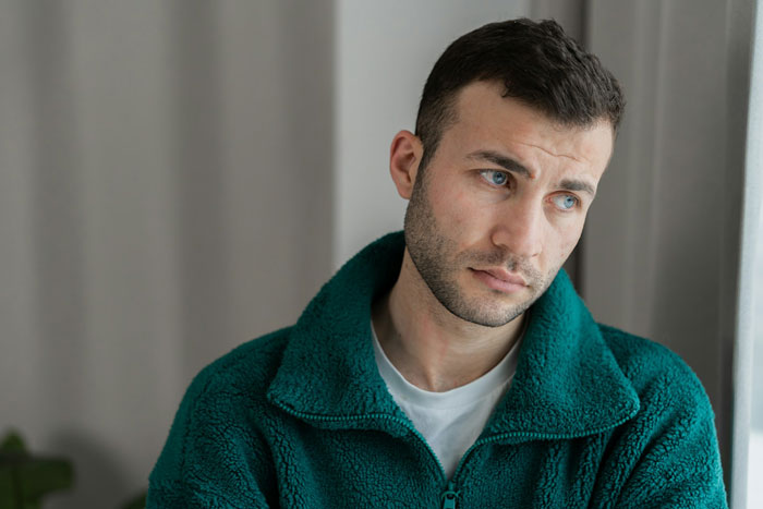 Young man in a teal fleece looking upset and contemplative, reflecting on family conflicts involving parenting and siblings. Young man in a teal fleece looking upset and contemplative, reflecting on family conflicts involving parenting and siblings.