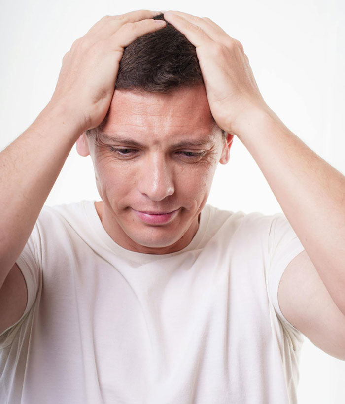 Stressed man in white shirt holding his head, depicting tension from woman going berserk over parenting and sibling meddling. Stressed man in white shirt holding his head, depicting tension from woman going berserk over parenting and sibling meddling.