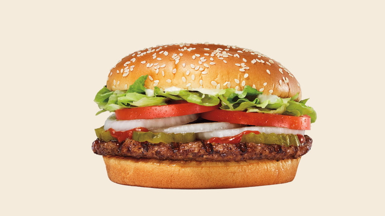 A whopper containing beef patty, cut tomatoes and onions, lettuce, and sesame buns