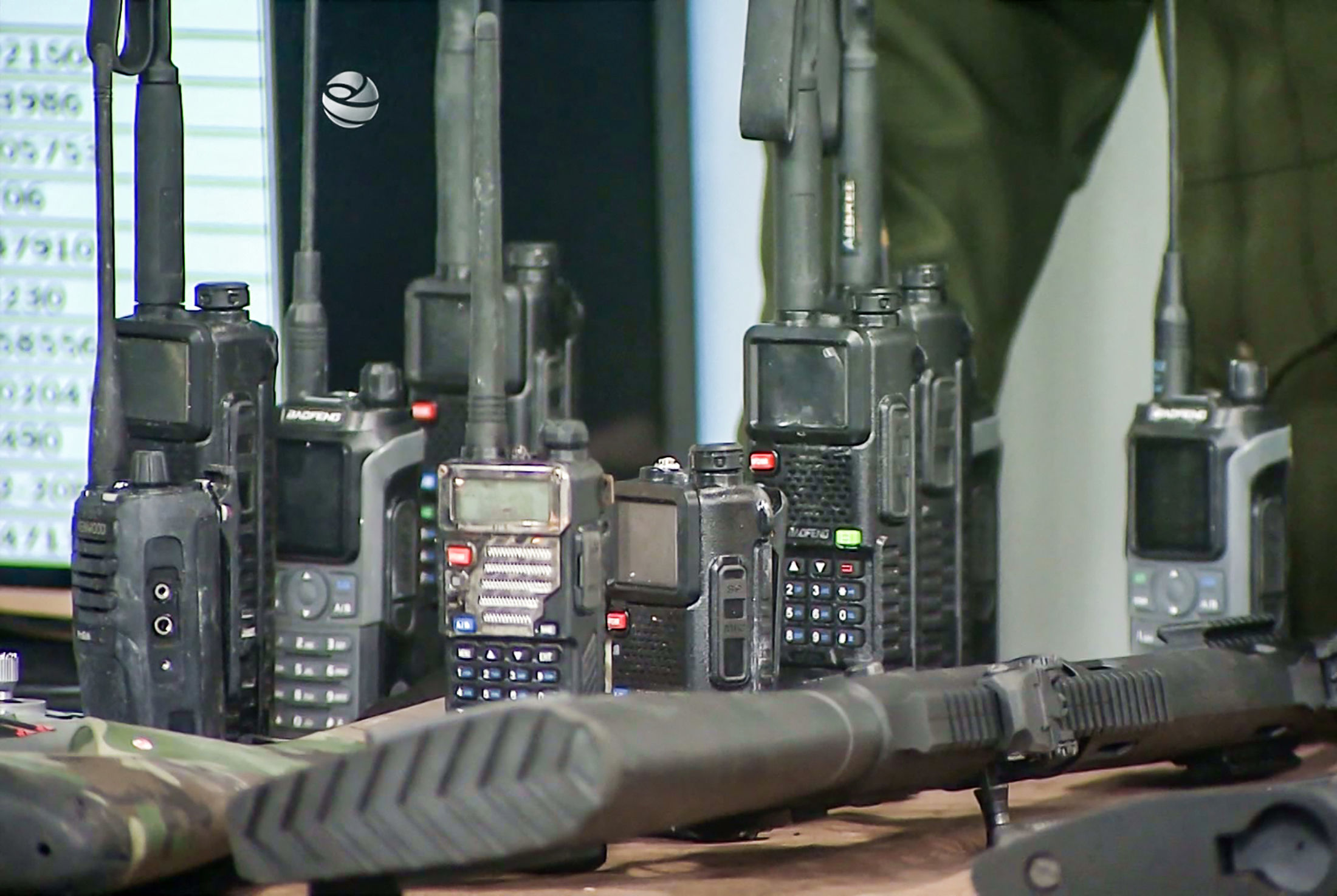 Seized weapons and radios displayed on a table.