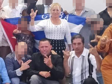 Maritza Lugo Fernández, Amijail Sánchez González, and Leordán Cruz Gómez making 'L' signs for 'libertad' with a Cuban flag.
