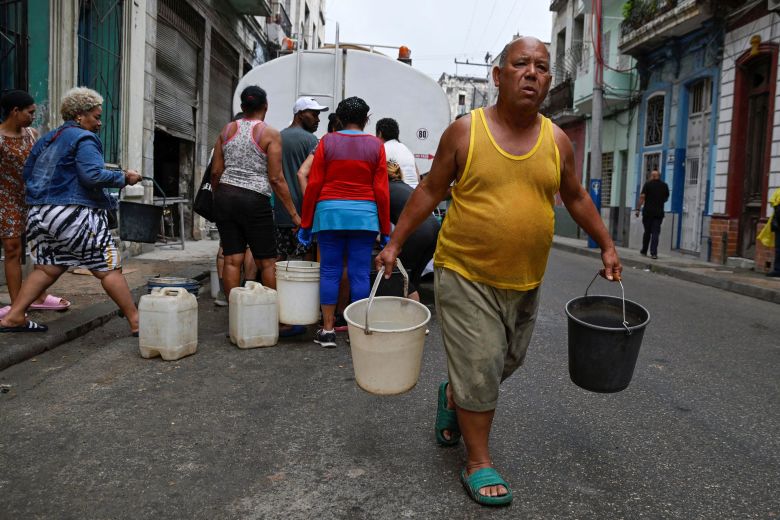 A man carries buckets of water on March 19 as severe fuel shortages have disrupted water pumping and distribution in Havana.