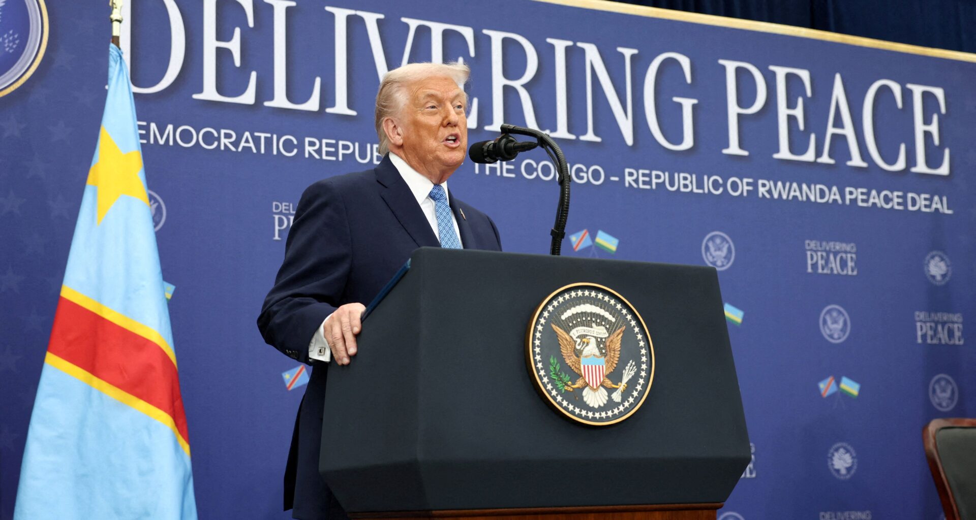 A crane lowers a white package containing food aid into a crate off of the side of a ship.