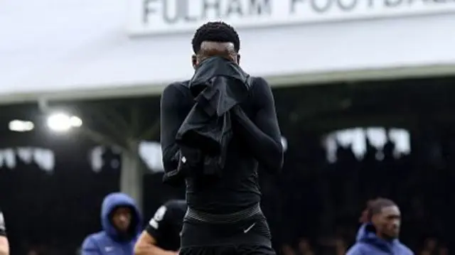 Pape Matar Sarr covers his face with his shirt at the full-time whistle against Fulham