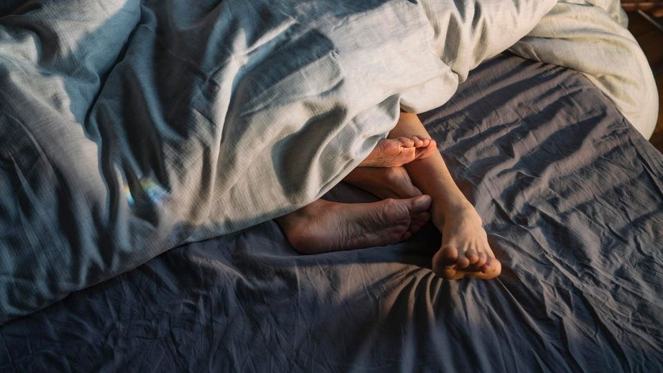 Couple's feet sticking out from under duvet in bed