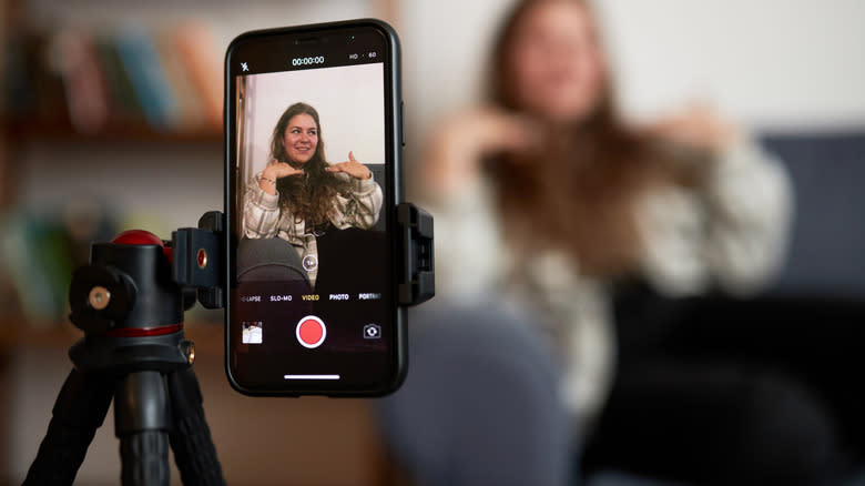 A woman talking in front of a smartphone on a tripod.