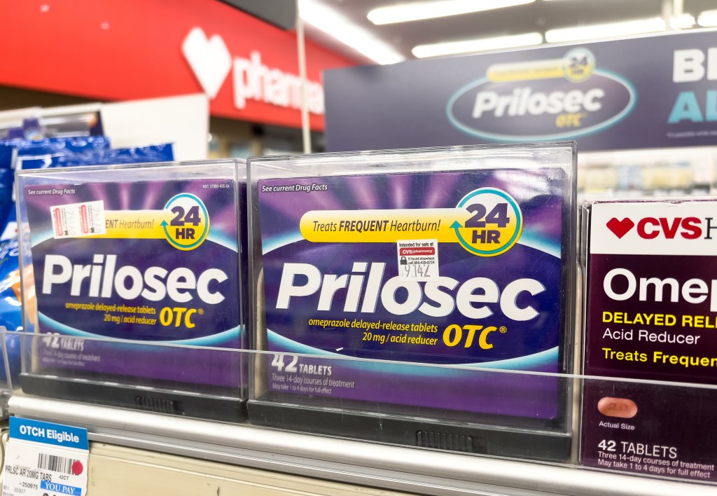 Packages of Prilosec brand frequent heartburn omeprazole delayed-release acid reducer tablets treatment for sale at a CVS pharmacy.