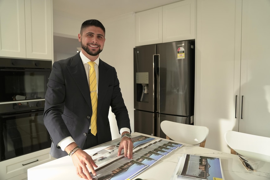 a man in a suit standing in a kitchen