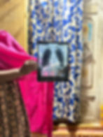 Hands hold up a chest X-ray in a dim room, with a door and a blue curtain in view.