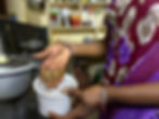 A woman picks dried prawns from a white plastic container.