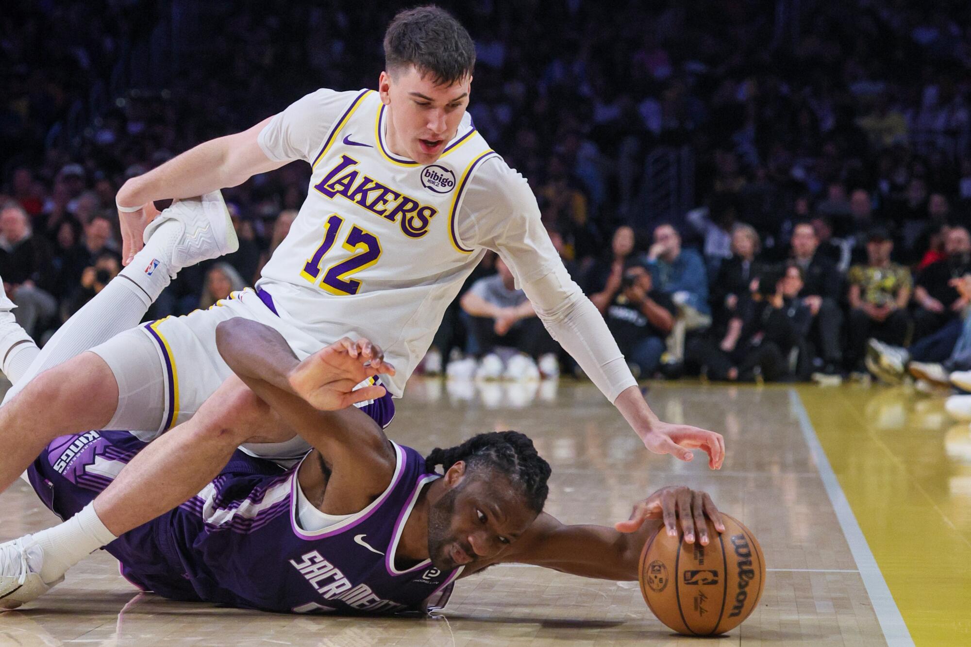 Lakers forward Jake LaRavia, top, and Sacramento forward Precious Achiuwa battle for the ball during the Lakers' win Sunday.