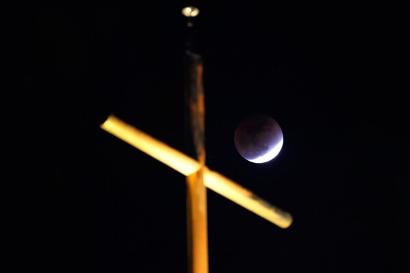 A total lunar eclipse is seen behind a cross over a church in Seoul, South Korea, Tuesday, March 3, 2026. (AP Photo/Ahn Young-joon)