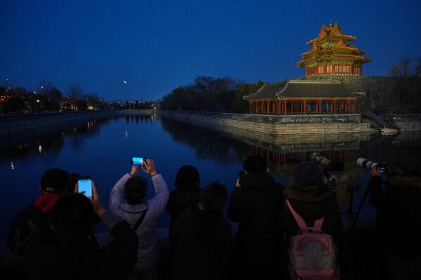 People film the lunar eclipse near the Forbidden City in Beijing, China, Tuesday, March 3, 2026. (AP Photo/Andy Wong)