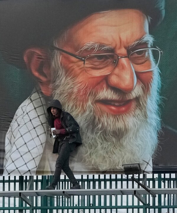 A worker helps install a billboard bearing a portrait of the late Iranian Supreme Leader Ayatollah Ali Khamenei, who was killed during the ongoing joint U.S.-Israeli military campaign, in Tehran, Iran, Monday, March 2, 2026. (AP Photo/Vahid Salemi)