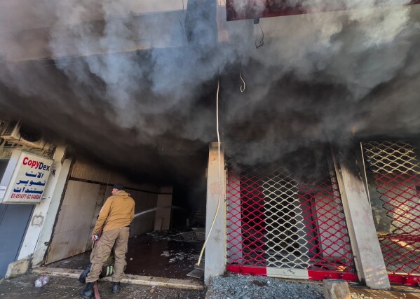 A firefighter sprays water on a building that was hit by an Israeli airstrike in Dahiyeh, a southern suburb of Beirut, Lebanon, Tuesday, March 3, 2026. (AP Photo/Hussein Malla)