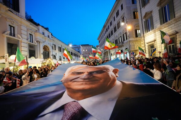 Demonstrators hold a banner with Iran's exiled Crown Prince Reza Pahlavi as they gather in Rome, Tuesday, March 3, 2026. (AP Photo/Alessandra Tarantino)