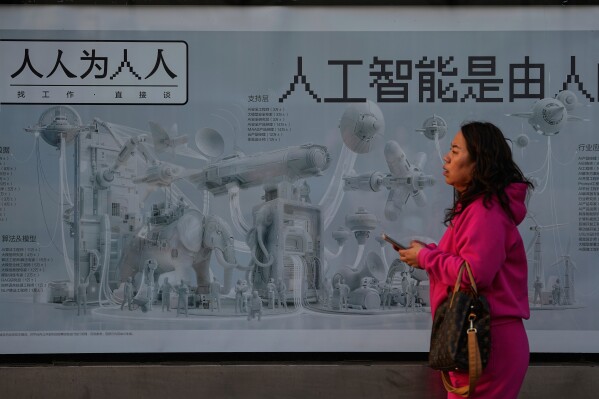 A woman walks past a job hunting advertisement poster carrying the words "Artificial intelligence is brought by human work" at a bus stand, in Beijing on Sunday, March 8, 2026. (AP Photo/Andy Wong)