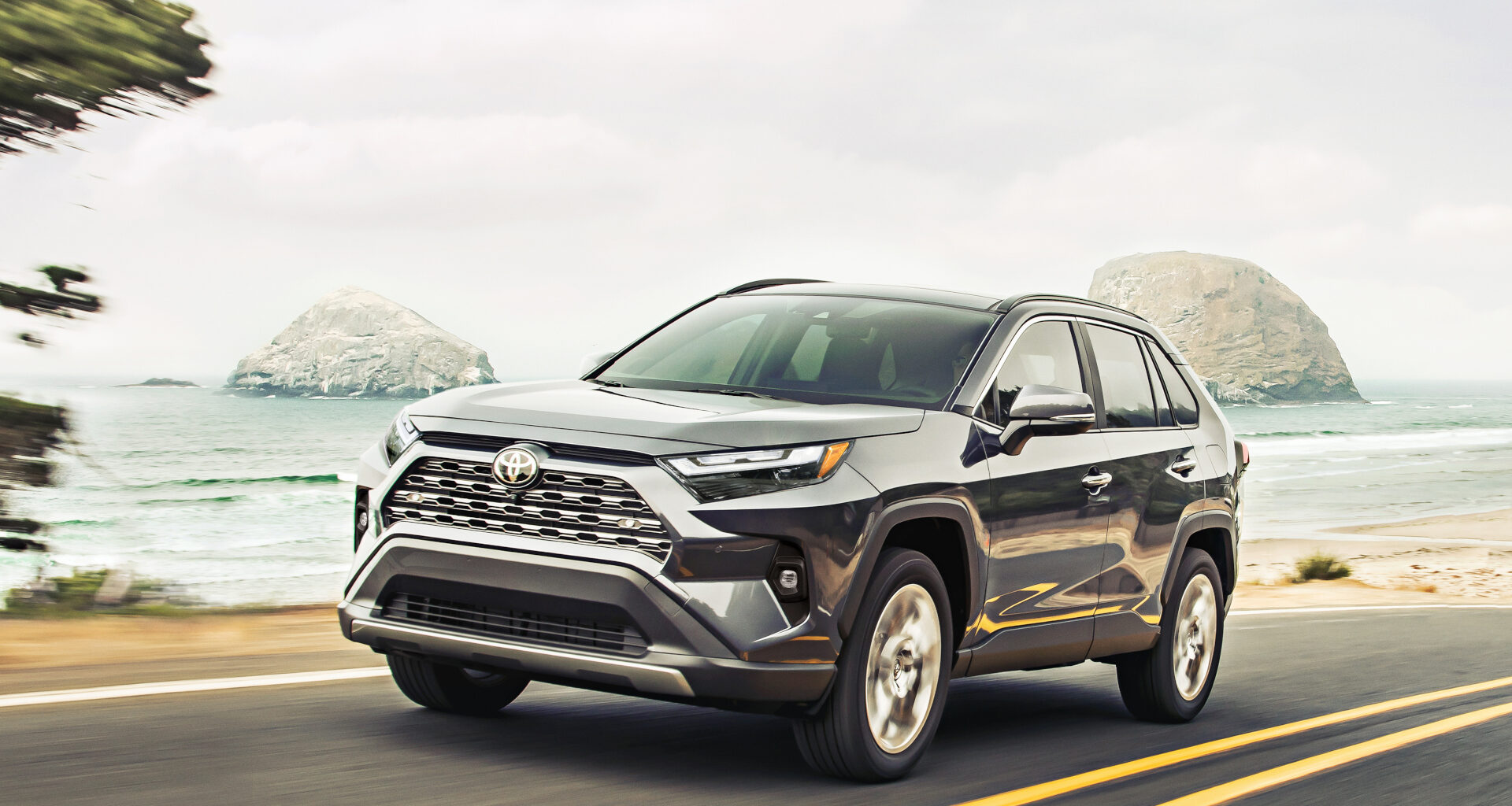 Toyota RAV4 driving down the road with a beach in the background.