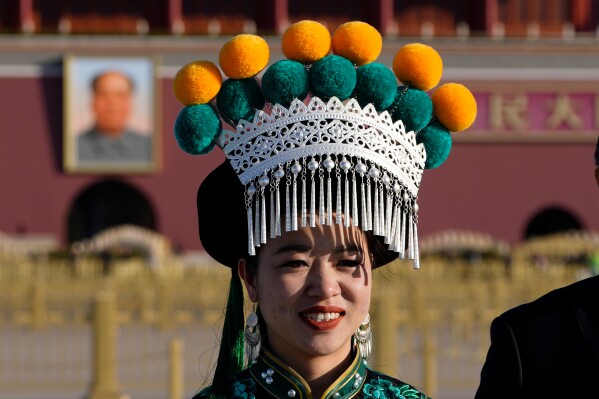 A ethnic minority delegate stand near Mao Zedong's portrait on Tiananmen Square before a plenary session of the National People's Congress (NPC) held at the Great Hall of the People in Beijing, Monday, March 9, 2026. (AP Photo/Ng Han Guan)