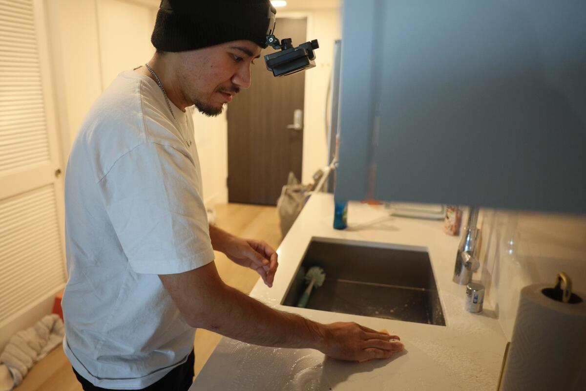 Arciga cleans a kitchen counter while wearing a headset