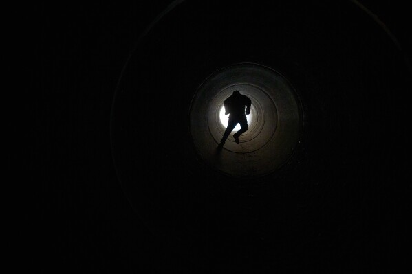 A boy runs inside a cement pipe turned into a bomb shelter as air raid sirens warn of incoming Iranian missile strike in Michmoret, Israel, Tuesday, March 10, 2026. (AP Photo/Ariel Schalit)