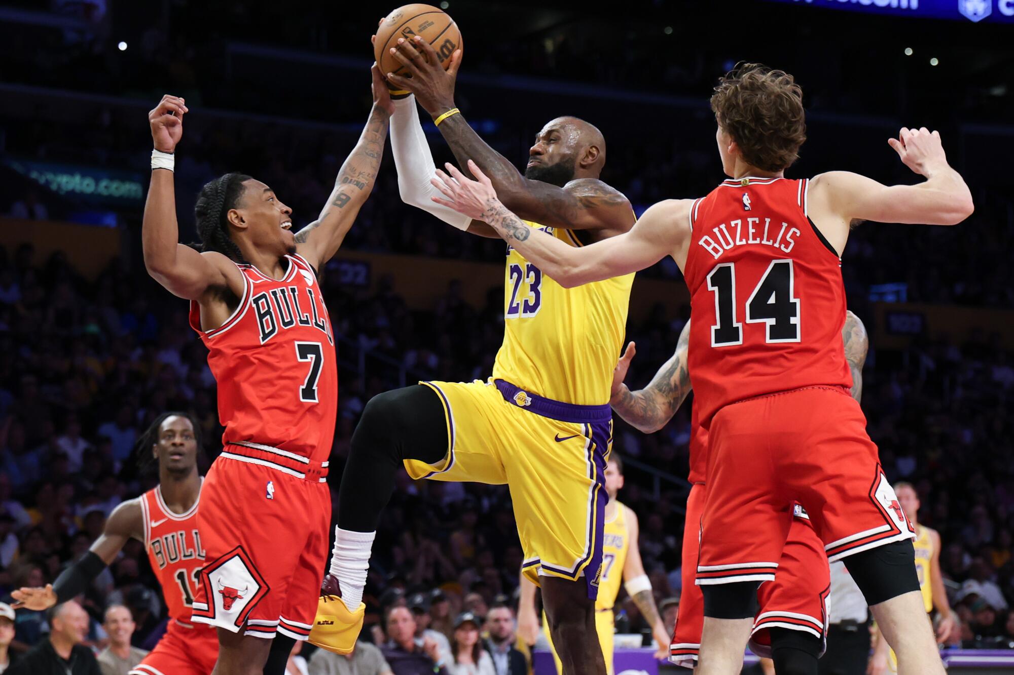 Lakers star LeBron James, center, drives between Chicago's Rob Dillingham, left, and Matas Buzelis.
