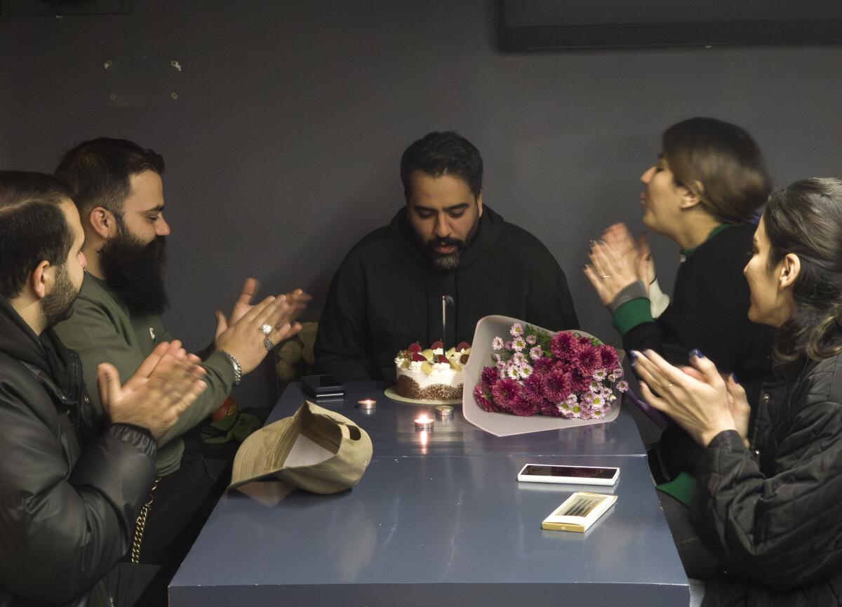 A young Iranian man makes a wish as he blows out a candle while his friends clap