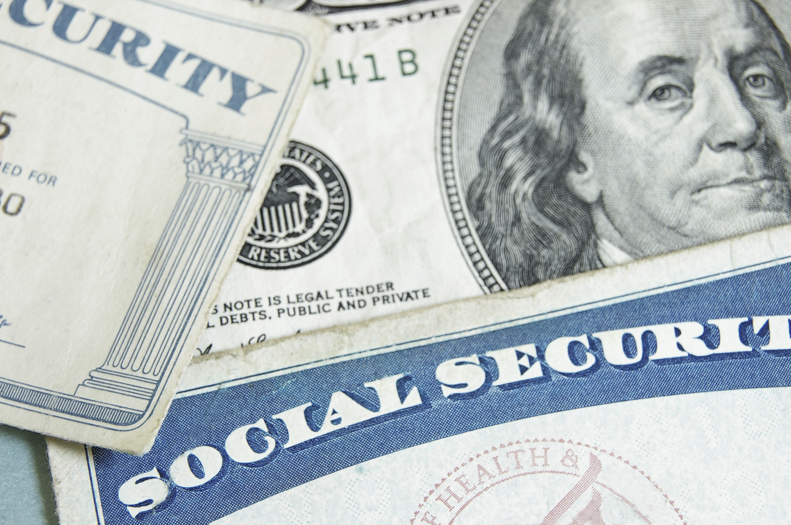 Two Social Security cards lay atop U.S. currency.